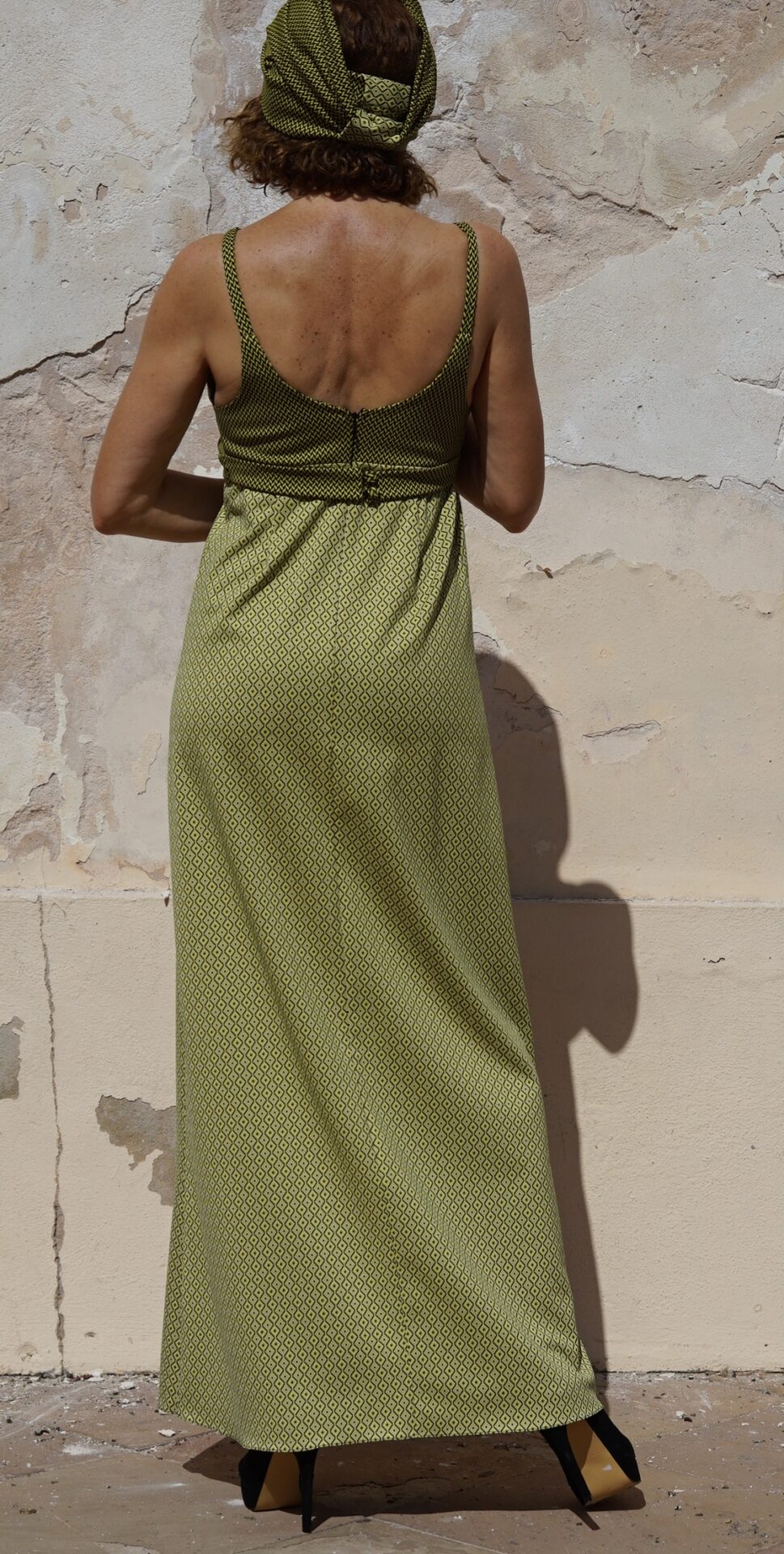 Vestido de cóctel largo de EVA TYCHÉ con dos estampados geométricos en verde y negro, escote cruzado en V y banda bajo el pecho. / Long cocktail dress by EVA TYCHÉ featuring two geometric prints in green and black, a crossover V-neckline and a band below the bust.