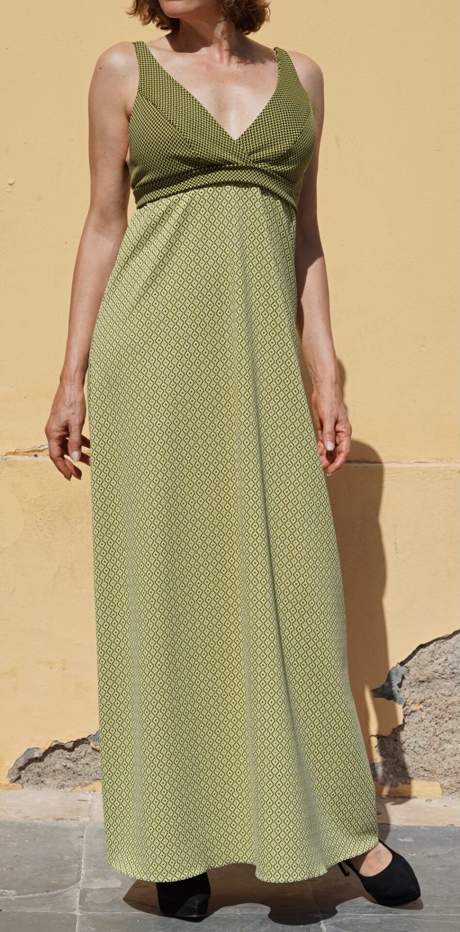 Vestido de cóctel largo de EVA TYCHÉ con dos estampados geométricos en verde y negro, escote cruzado en V y banda bajo el pecho. / Long cocktail dress by EVA TYCHÉ featuring two geometric prints in green and black, a crossover V-neckline and a band below the bust.